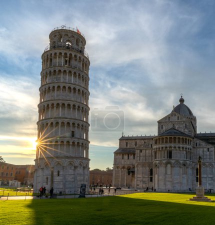 Photo for Pisa, Italy - 30 November, 2022: the Leaning Tower of Pisa and the Cathedral in warm evening light with a sunburst - Royalty Free Image