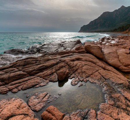 Téléchargez les photos : Vue sur la plage de Coccorocci avec piscines à marée dans la pierre rouge et une vue sur la côte accidentée de la Sardaigne - en image libre de droit