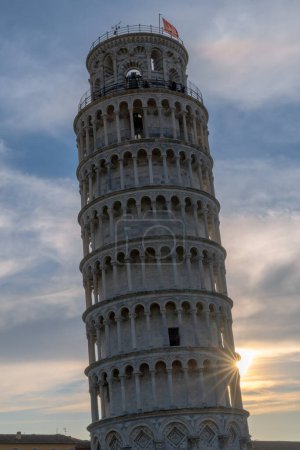Photo for Pisa, Italy - 30 November, 2022: vertical view of the Leaning Tower of Pisa at sunset with a sunburst - Royalty Free Image