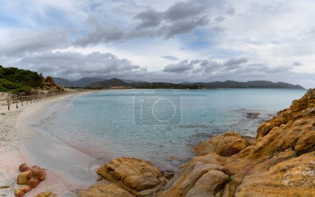 Foto de Vista del paisaje Porto Giunco Playa cerca de Villasimius en Cerdeña con cantos rodados de granito rojo en primer plano - Imagen libre de derechos