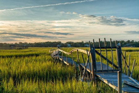 Téléchargez les photos : Vieux quai en bois délabré dans le marais et l'inlet de l'île Palweys en Caroline du Sud au coucher du soleil - en image libre de droit