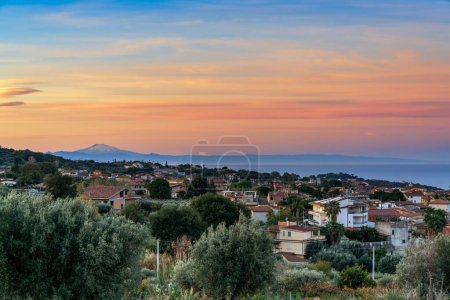 Blick auf das Dorf Ricadi in Kalabrien bei Sonnenaufgang mit Sizilien und dem Ätna im Hintergrund