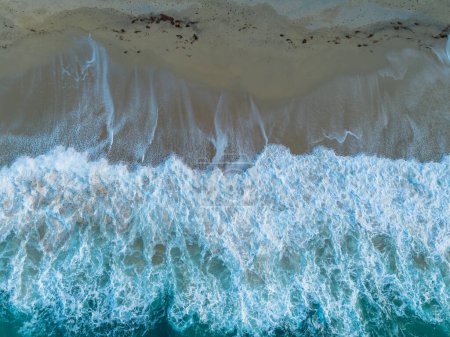 Une vue du haut vers le bas de la plage de sable doré Rotonda à Tropea avec de l'eau turquoise et des vagues s'écrasant sur le rivage