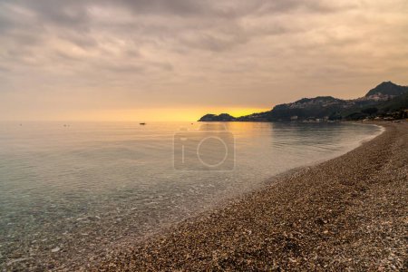 Foto de Una vista de la playa de guijarros de piedra y agua clara en Letojanni en Sicilia al sol - Imagen libre de derechos