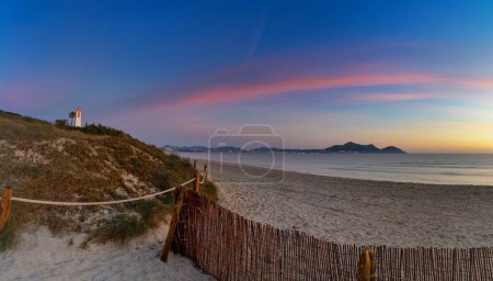 picturesque Playa del Muro beach with sand dunes and a view of the historic maritime observation towers and the town of Alcudia in the background