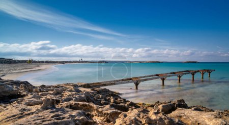 Ein altes Dock führt hinaus in das türkisfarbene Wasser des Strandes von Ses Illetes im Norden Formenteras.