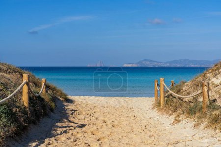 A beach access leads to Ses Illetes beach on Formentera with a view of Ibiza and Es Vedra in the background