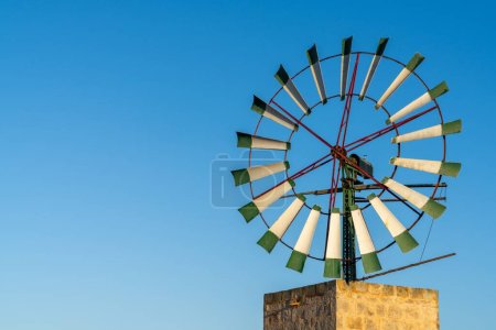 Foto de Una vista de cerca de un moderno molino de viento con cuchillas de acero en el interior de Mallorca bajo un cielo azul - Imagen libre de derechos