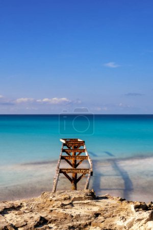 Ein altes Dock führt hinaus in das türkisfarbene Wasser des Strandes von Ses Illetes im Norden Formenteras.