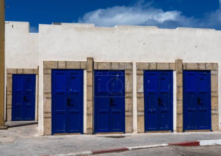 Vue minimaliste des portes bleues dans le mur portuaire du vieux port d'Essaouira