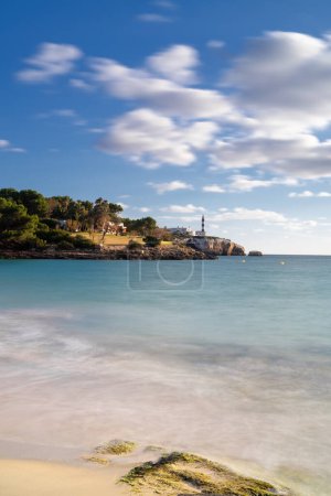 Une vue sur la plage Arenal dets Ases et le phare de Portocolom en arrière-plan