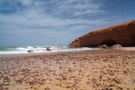 Une longue vue d'exposition de la plage et de l'arche rocheuse à Legzira sur la côte atlantique du Maroc