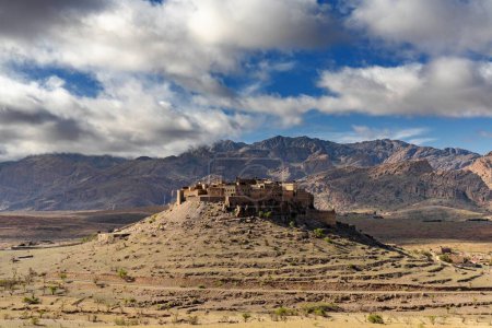 A landscape view of the Altas mountains in Morocco with the Kasbah Tizourgane on the hilltop in the centre