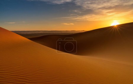 A view of the sand dunes at Erg Chebbi in Morocco at sunset with a sunstar
