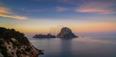A panorama landscape view of the landmark Es Vedra island and rocks off the coast of Ibiza at sunrise