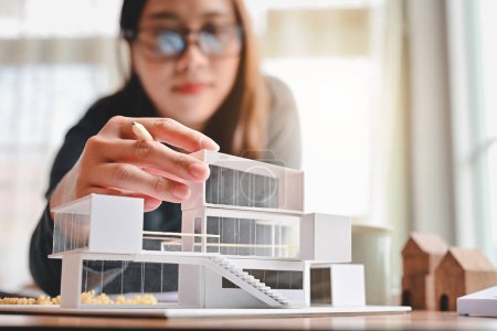 Photo for Undergraduate architecture students work on models of the modern box house. Holding the part of the model while thinking about concepts of building and construction. Focusing on her hand. - Royalty Free Image