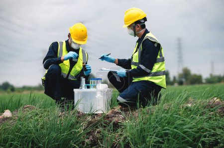 Photo for Two Environmental Engineers Inspect Water Quality and Take Water Samples Notes in The Field Near Farmland, Natural Water Sources maybe Contaminated by Toxic Waste or Suspicious Pollution Sites. - Royalty Free Image