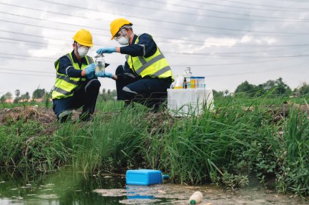 Two Environmental Engineers Inspect Water Quality and Take Water Samples Notes in The Field Near Farmland, Natural Water Sources maybe Contaminated by Toxic Waste or Suspicious Pollution Sites.