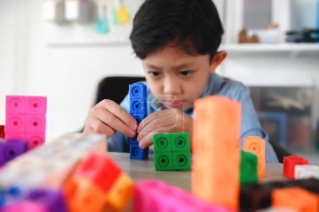 Foto de Niño pequeño asiático jugando cubos de plástico coloridos en el escritorio en casa. Aprendizaje y educación sobre contar cubos en matemáticas, desarrollar el cerebro y la meditación mientras se juega. - Imagen libre de derechos