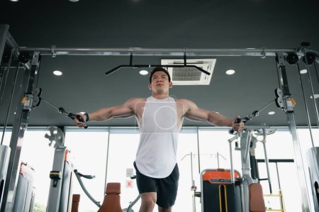 Photo for Muscular man, Bodybuilder Asian man workout doing cable rope pushdowns. Tricep arm exercises balanced upper body pull-downs with cable machine weight lifting in gym, Fitness exercising concept. - Royalty Free Image
