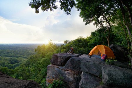 Female Travelers Pitch Vibrant Orange Tent on Cliff with a Natural View. Sitting Relax on Cliff, Embracing Pristine Natural Views or Surrounded by Cliffside Beauty, Unforgettable Camping Journey.