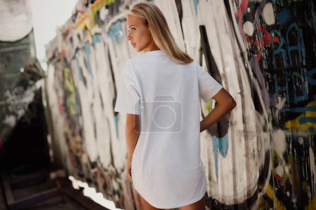 Photo for Blond girl in white t - shirt and shorts  near graffiti wall - Royalty Free Image