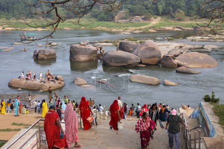 Téléchargez les photos : Les pèlerins prennent leur bain dans la rivière Tugabhadra près du temple VVirupaksha à Hampi - en image libre de droit