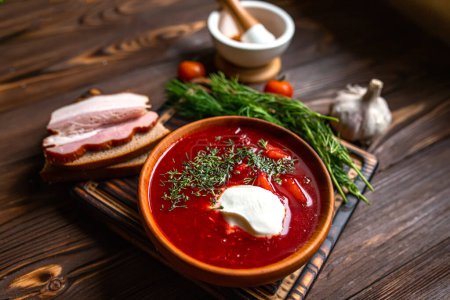 Traditional Ukrainian Russian borscht or red soup in bowl. Board with set of vegetables for cooking on dark wooden background