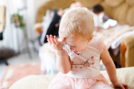 Photo for The baby wipes her nose with a napkin. the child in the apartment is isolated during illness and allergies. - Royalty Free Image
