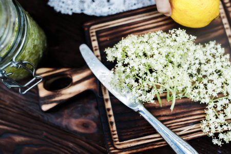 Téléchargez les photos : Ingredients for a refreshing drink of elderberry and lemon. Knife on a cutting board. - en image libre de droit