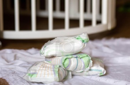 Téléchargez les photos : A bunch of dirty used diapers on the floor near the crib. Discarded diapers without a bucket in the nursery. - en image libre de droit