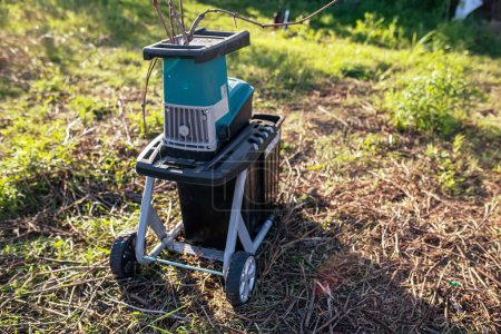 Photo for Electric garden grinder to shred with a extended filled tank for crushed branches, ready for use in solid fuel boilers, or as mulch for garden work - Royalty Free Image