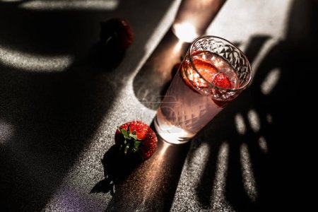 Photo for Refreshing strawberry lemonade. Cool and fruity beverage with a hint of citrus. Glass filled with ice-cold strawberry and lemon juice on a dark background - Royalty Free Image
