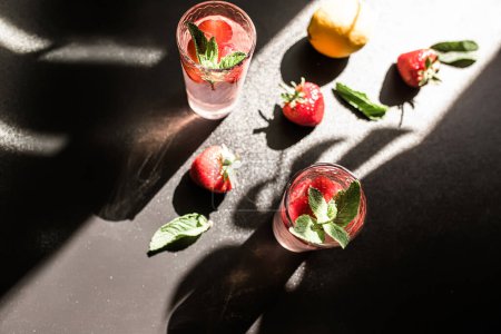 Photo for Berrylicious strawberry mojito. tropical twist on classic cocktail. Fresh strawberries, lime, and mint leaves combine to create vibrant and flavorful drink. Served over ice in glass on dark background - Royalty Free Image