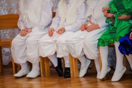 Photo for Children sit on a chair on children. Boys dressed in costumes rabbits. Young children lay hands on lap. - Royalty Free Image