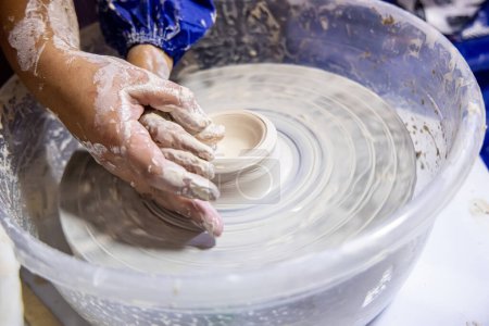 Photo for Hands of a clay sculpting teacher while teaching a child on a potter's wheel - Royalty Free Image