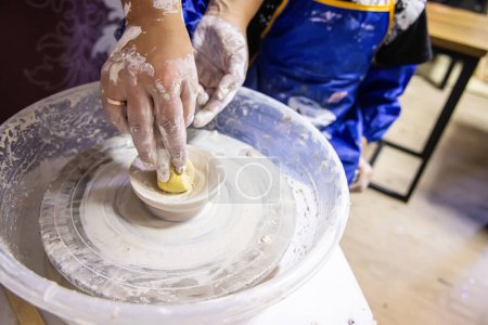 Téléchargez les photos : Le professeur enseigne aux enfants à sculpter à partir d'argile sur une roue de potier. Leçon de poterie - en image libre de droit