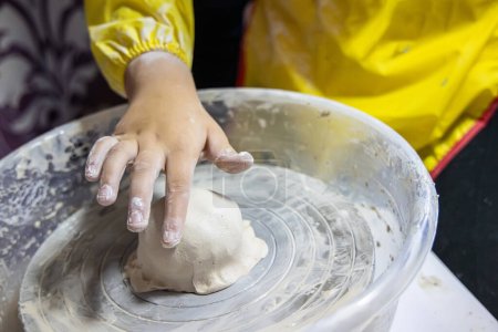 Téléchargez les photos : Professeur guide soigneusement les mains de l'enfant sur la roue de poterie - en image libre de droit