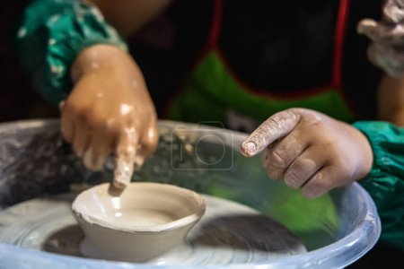 Téléchargez les photos : Enfant essaie leur main à façonner une plaque de céramique sur la roue du potier. - en image libre de droit