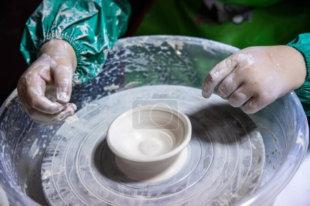 Téléchargez les photos : Jeune potier en formation prend le volant pour confectionner son propre chef-d'œuvre de poterie - en image libre de droit