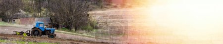 Foto de Viejo tractor azul con arado en el campo y cultiva el suelo. Preparación de la tierra para plantar verduras en primavera. Maquinaria agrícola, trabajo de campo. - Imagen libre de derechos