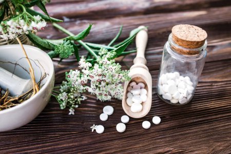 Téléchargez les photos : Valerian tablets with sedative properties. Pharmaceutical jar with pills on a wooden table. Cooking Valerian Root in a Mortar for Herbalism Elixirs. Soft focus - en image libre de droit