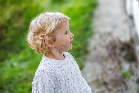 Photo for Surprised little girl in white sweater. Children's emotions. A child on the background of the grass in autumn. - Royalty Free Image
