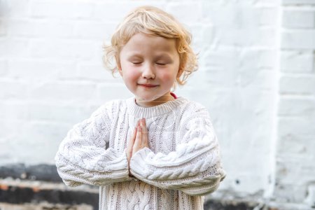 Photo for Tender moment as the child folds their hands in prayer, eyes closed in reverence. - Royalty Free Image