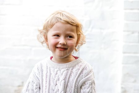 Photo for Little cute girl in a warm white sweater smiling. Portrait of a 4-year-old girl - Royalty Free Image