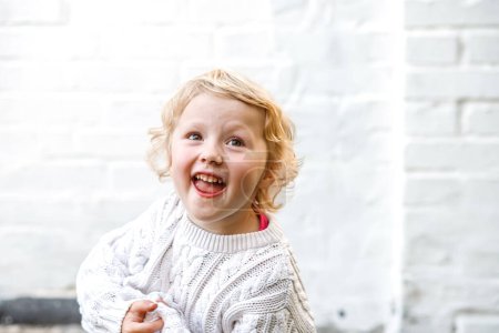 Photo for Funny girl indulges and smiles. Portrait of a funny 4-year-old girl - Royalty Free Image
