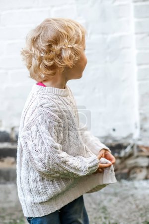 Photo for Despite the worry in their eyes, the child smiles sweetly while holding onto their clothes. - Royalty Free Image
