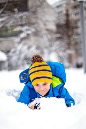 Téléchargez les photos : Petit garçon mignon s'amusant avec de la neige dans le parc d'hiver. Enfant heureux jouant avec la neige dans le parc d'hiver. - en image libre de droit