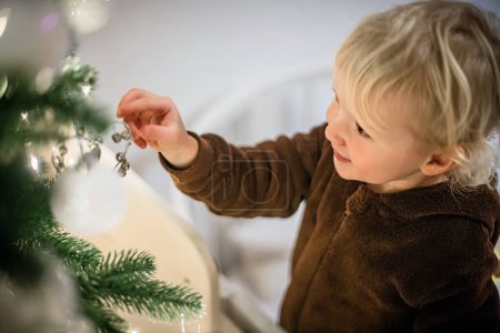 Téléchargez les photos : Petite fille mignonne debout près de l'arbre de Noël et pointant du doigt - en image libre de droit