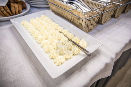 Téléchargez les photos : Portions de beurre à étaler sur du pain dans une assiette. Restauration buffet intérieur dans un restaurant de luxe avec de la viande de fruits et légumes colorés - en image libre de droit